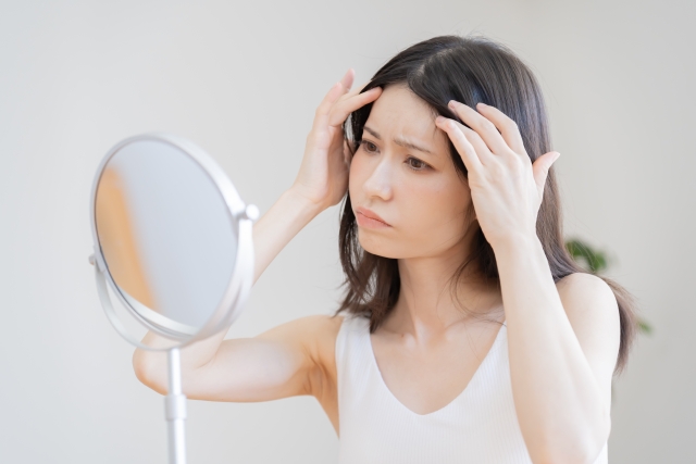 40代女性が鏡を見て白髪を気にしている様子｜白髪が急に増えた悩み