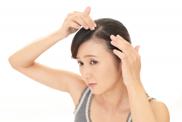40代女性が鏡を見て白髪を気にする様子